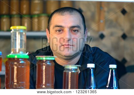 BAKU, AZERBAIJAN - MAY 4 2014 
Honey seller at a Baku market. Man at popular market in central Baku, the capital city, sitting behind jars of home produced honey