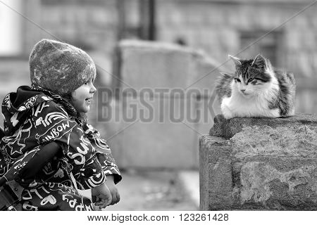 Young girl in pushchair with stray cat in Baku, capital of Azerbaijan. Black and white image showing affection from infant girl towards a long haired stray cat