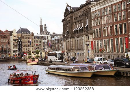 AMSTERDAM, THE NETHERLANDS - AUGUST 19, 2015: View on Rokin from bridge Doelensluis. Street life, Canal, tourists, bicycle and boat in Amsterdam. Amsterdam is capital of the Netherlands on August 19, 2015.