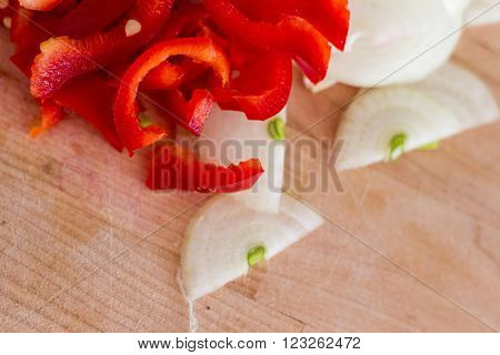 Chopped onion and pepper on a wooden board close up