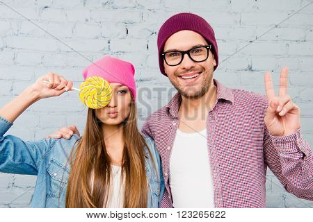 Woman Holding Lollipop Near Eyes  And Man Gesturing With Two Fingers