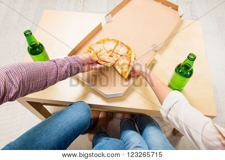 Top view of two friends eating pizza and drinking beer