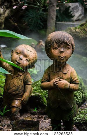 Statue of two children, the background trees.