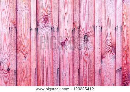 A fragment of a wooden fence. Wooden boards as a background with copy space. Wooden rustic wood boards background texture pink.