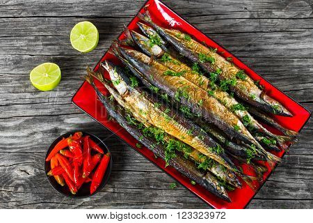 Baked saury on a red rectangular dish close-up top view