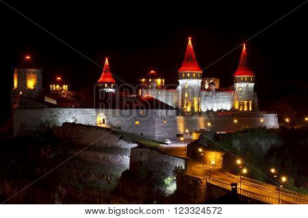 Beautiful medieval castle at night, colored lights historical attractions