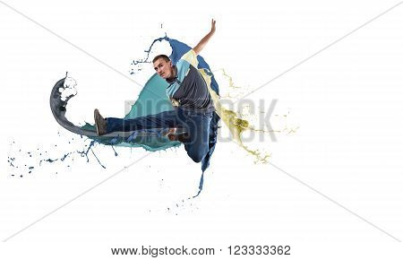 Young male dancer in jump on white background with colorful paint plashes