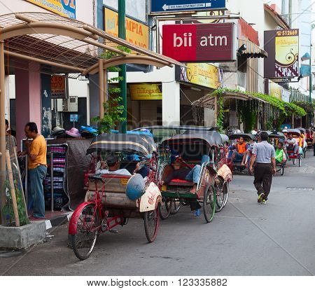 YOGYAKARTA - AUGUST 03: Traditional rikshaw transport on streets of Yogyakarta, Java, Indonesia on August 03, 2010. Bicycle rikshaw remains popular means of transport in many Indonesian cities.