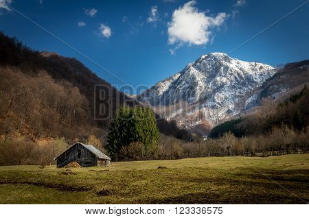 Panoramic view of beautiful mountain landscape in spring. Springtime in mountains. There are a chalet in the meadow.