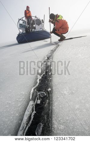 Saint-Petersburg, Russia - March 27, 2016: A member of the rescue team checks the thickness of the ice in the Gulf of Finland where the ice fishermen out.
