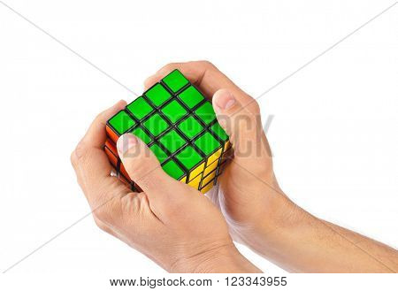 MOSCOW, RUSSIA - August 31, 2014: Hands and Rubik's cube puzzle isolated on the white background. Cube was invented by a Hungarian architect Erno Rubik in 1974.