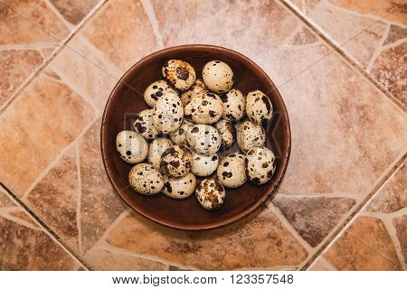 quail eggs are in the clay plate on tiled floor