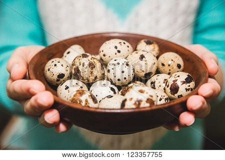 quail eggs are on the brown table in the hands