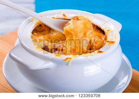 french onion gratin soup in a white pot close-up