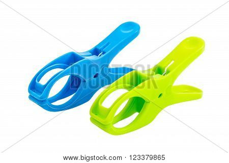 Closeup of two plastic spring clamps (Blue, Green) isolated over white background.