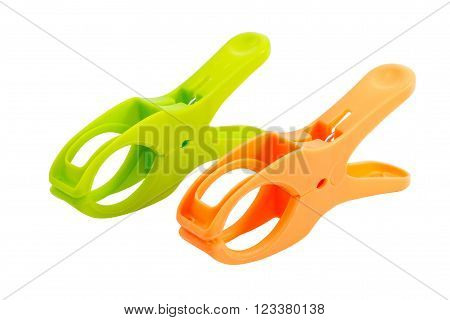Closeup of two plastic spring clamps ( Green, Orange) isolated over white background.
