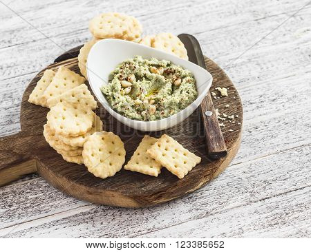 Healthy vegetarian broccoli and pine nuts hummus and homemade cheese biscuits on a wooden rustic board. Delicious snack or appetizer with wine