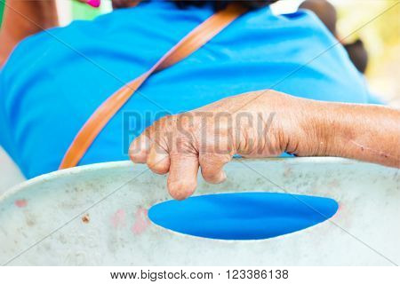 closeup hand of old man suffering from leprosy on the backrest of plastic chair.