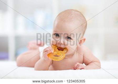 baby little child lying on bed weared diaper with teether