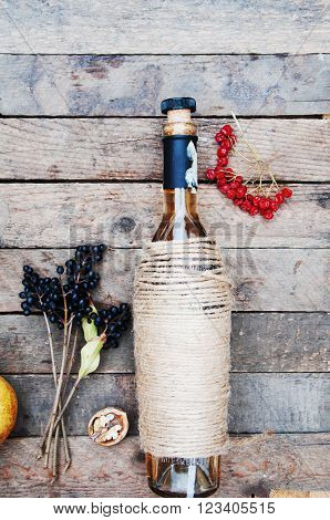 The still life with white wine in glass bottle on wood background. Glasses of wine with fresh grapes. Bottle and footed glass. Fresh ripe white grapes walnuts juicy ripe pear. Drink. Rustic style.