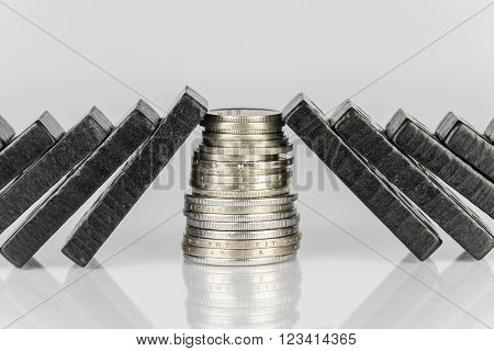 Conceptual composition of falling black domino stones as a continuous process and a pile of coins which disrupt this main process