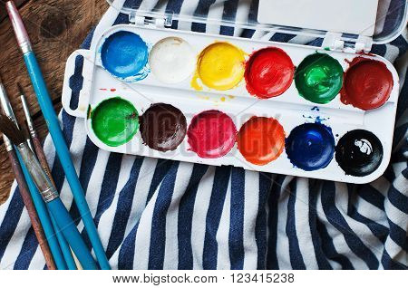 Art of Painting. Paint buckets on wood background. Different paint colors painting on wooden background. Painting set: brushes paints crayons chalk watercolor acrylic paint on a wooden background