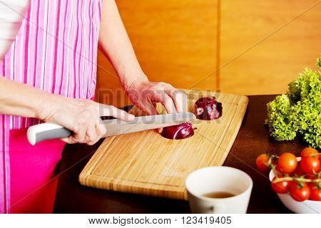 Woman cut red onion on cutting board