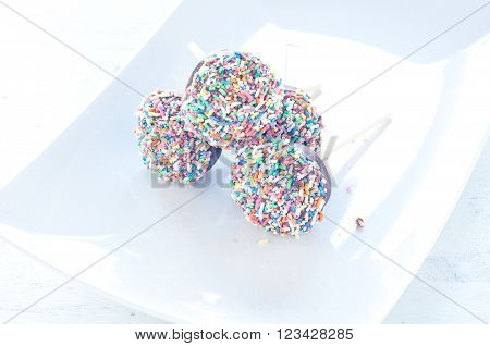 Small cupcake with chocolate in the shape of Chupa Chups decorated with sugar