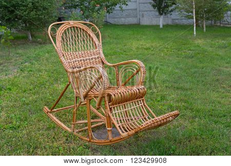 Wicker rocking-chair in the summer garden .