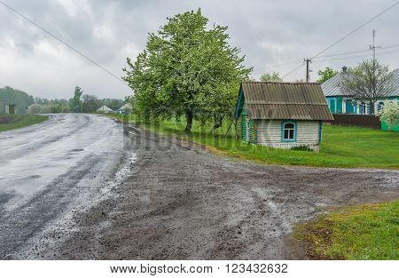 Landscape with draw-well as a small wooden house at roadside in Lyubka village, Sumskaya oblast, Ukraine