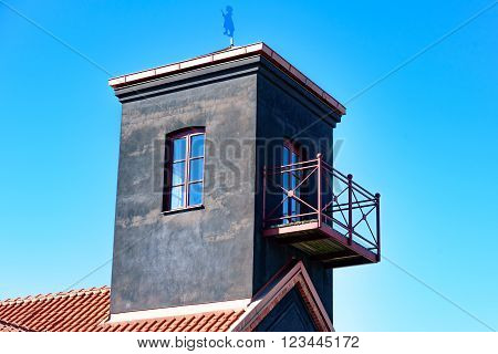Ahus Sweden - March 20 2016: Detail of the hose tower on the old fire station building by the harbor promenade. Inside the firemen dried their fire hoses after use. Metal firefighter on rooftop.