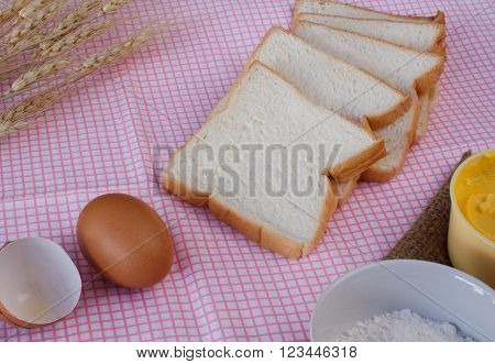 Still life with sliced breadegg flour magarine and wheat on table