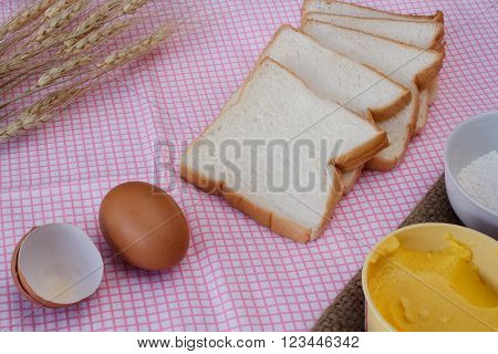 Still life with sliced breadeggflourmagarine and wheat on table