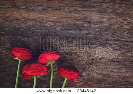 posy of red ranunculus flowers on wooden nackground, retro toned