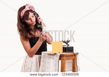 Fashion young woman with a retro look speaks at a vintage phone and reads from a bottle with medicine