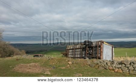 Farm tractor trailor lying on its side in Wooler