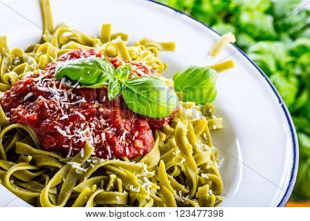 Pasta. Italian and Mediterranean cuisine. Pasta Fettuccine with tomato sauce basil leaves garlic and parmesan cheese. An old home kitchen with old kitchen utensils.