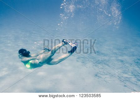 Caucasian girl swimming underwater with a cloud made of boobles