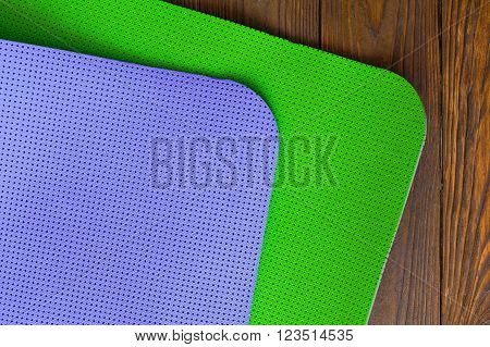 New yogamat green and purple on a wooden background. Facilities for training and yoga.  The concept of love to a healthy lifestyle. Weight loss and fitness. Diagonal.