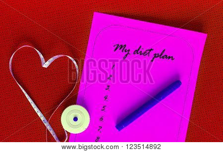 Diet plan on a pink sheet of paper. List yogamat on a background of red. Measuring tape in the shape of a heart. The concept of love to a healthy lifestyle. Weight loss and fitness.