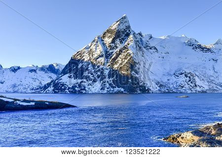 Fishing hut (rorbu) in the Hamnoy and Lilandstinden mountain peak in winter in Reine Lofoten Islands Norway.