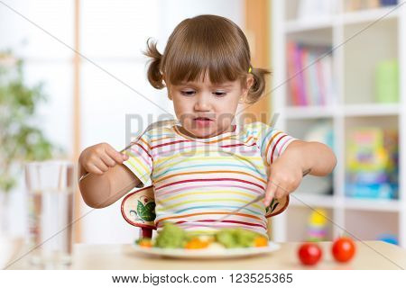 Little child girl refusing to eat her dinner or lunch