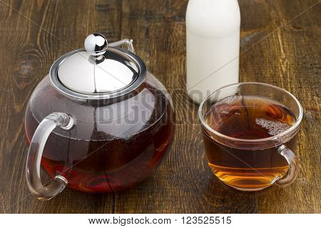 Set of glass teapot and bottle of milk on wooden table