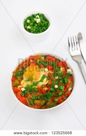 Shakshuka with egg in white bowl close-up on a white background top view. Healthy food.