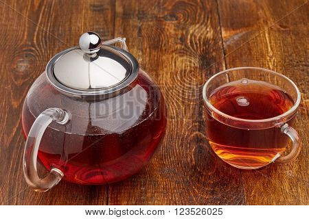 Set of glass hot teapot and cup of tea on wooden table