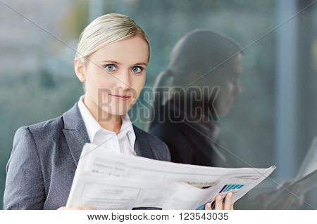 A young businesswoman reading the newpaper outside her office