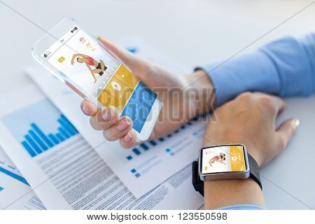 sport, fitness, technology, responsive design and people concept - close up of female hand holding smart phone and wearing watch with sports application on screen
