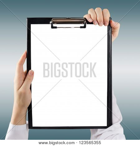 Female doctor's hand holding medical clipboard with blank sheet of paper on blie blurred background. Concept Healthcare And Medicine. Copy space.