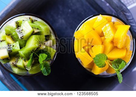 Dietetic dessert in the form of a fresh fruit salad with kiwi and peach with chia seeds and yoghurt served in a glass.Looking at the scene from above.