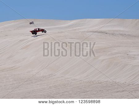LANCELIN,WA,AUSTRALIA-SEPTEMBER 28,2015: Dune buggy recreational vehicle jumping the white sand dunes on a clear day in Lancelin, Western Australia.